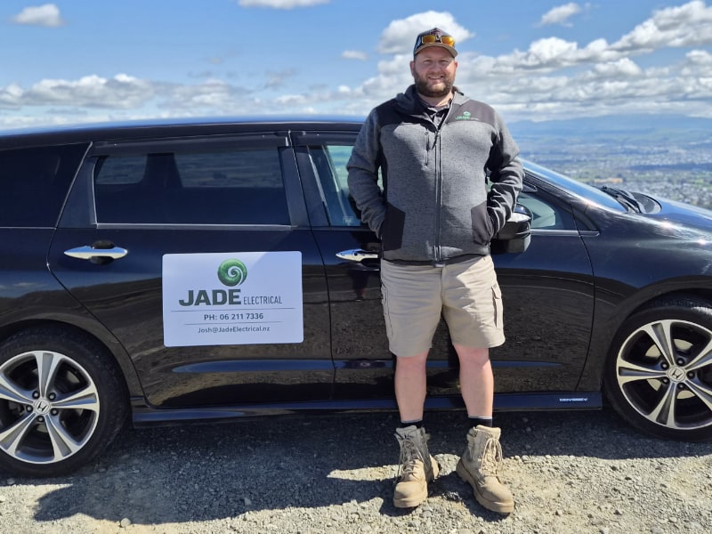 Josh in JADE-branded uniform standing beside the work van, Hawke's Bay setting